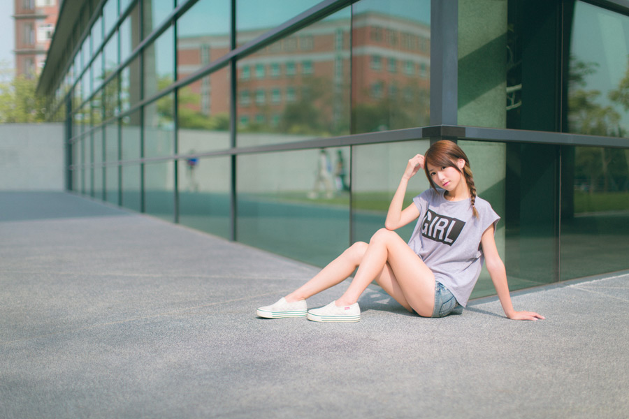 フリー 写真Tシャツとショートパンツ姿で建物の角に座る女性