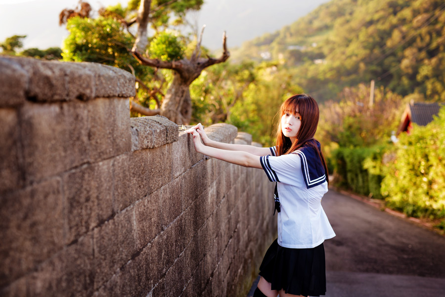 フリー写真 セーラー服姿でブロック塀に手をつく女子高生