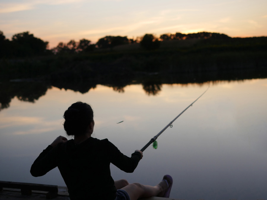 フリー写真 夕暮れの湖で釣りをしている女性