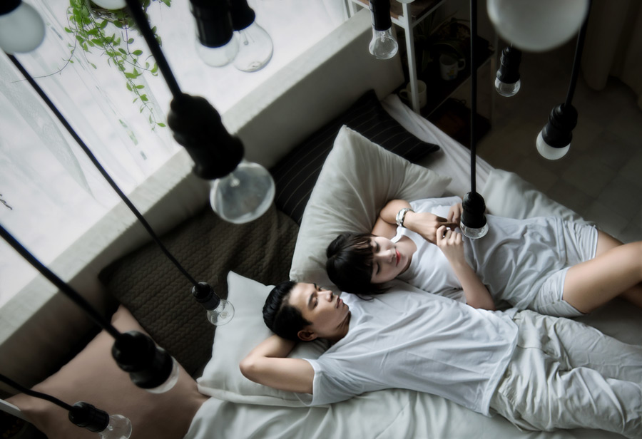 フリー写真 ベッドの上で仰向けになって眠るカップル