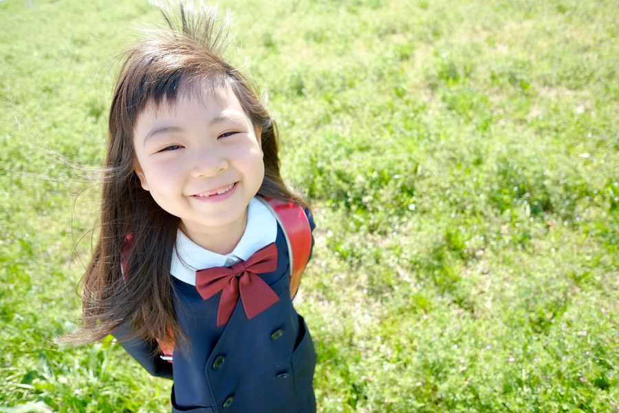 フリー写真 草むらで微笑む小学生の女の子