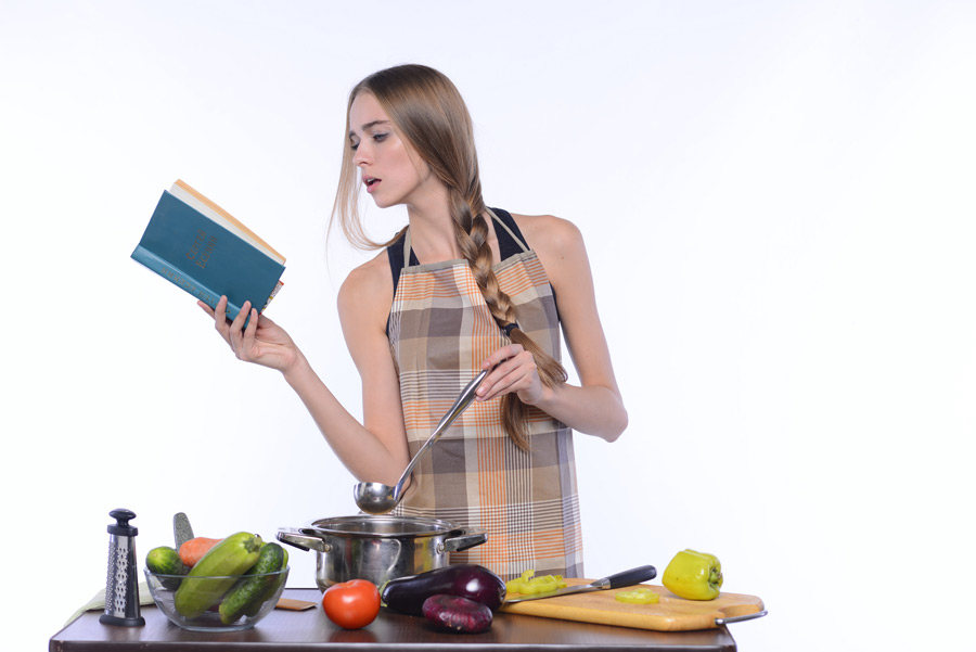 フリー写真 料理本を見ながら調理中の外国人女性