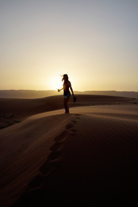 フリー写真 夕日と砂漠に立つ女性