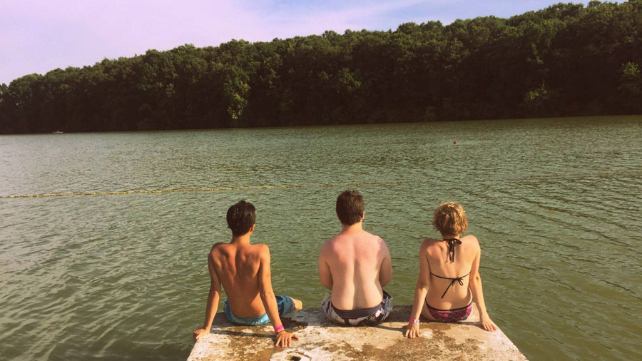 フリー写真 湖の前の堤防に座る三人の男女